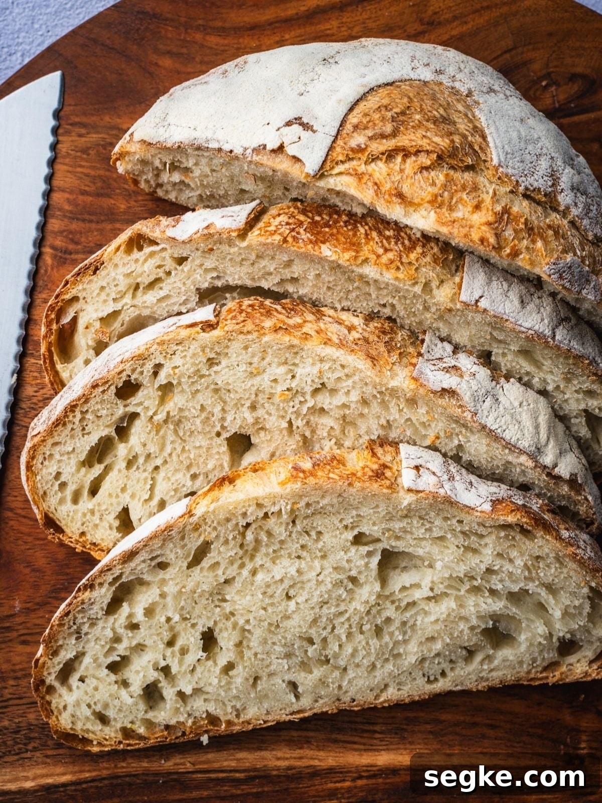 How to Make No-Knead White Bread at Home 2 A loaf of no knead white bread sliced on a wooden board.