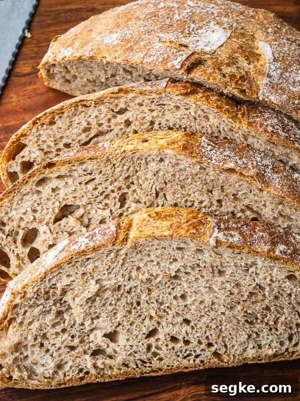 How to Make No-Knead White Bread at Home 11 Sliced no knead whole wheat bread on a wooden cutting board.