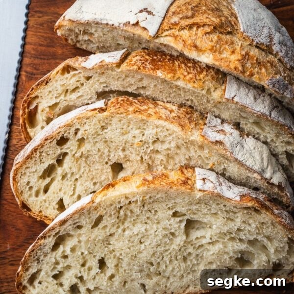 How to Make No-Knead White Bread at Home 13 A loaf of no knead white bread sliced on a wooden board.