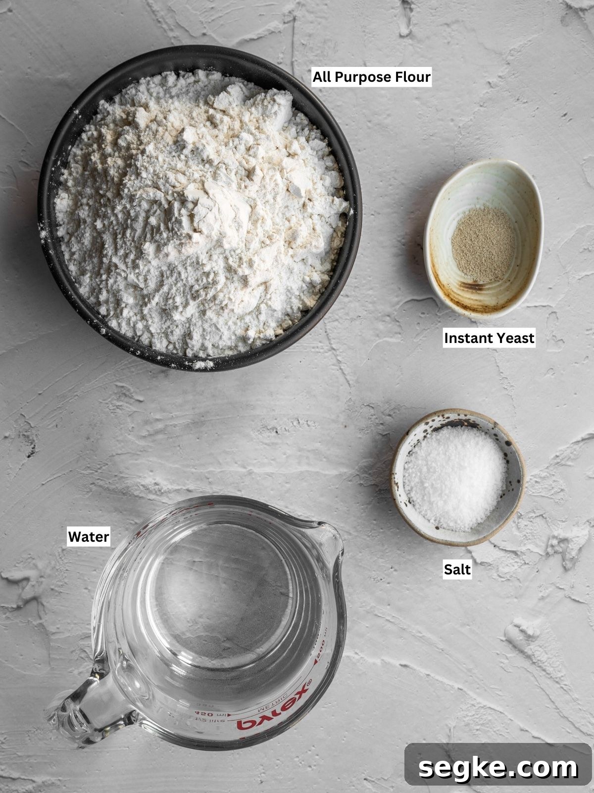 How to Make No-Knead White Bread at Home 3 No knead white bread recipe ingredients with individual labels on a board.