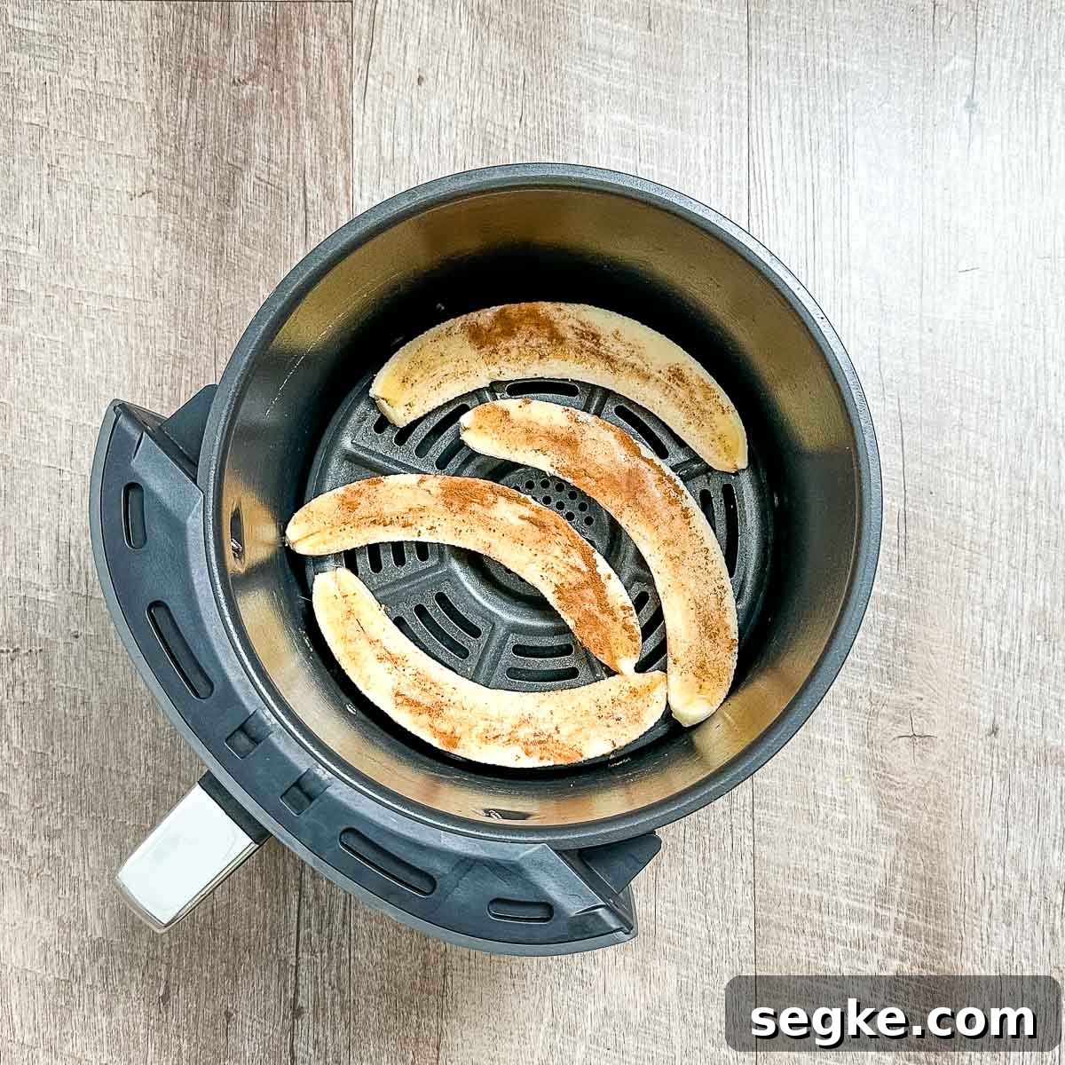 Bananas brushed with maple syrup and dusted with cinnamon in the air fryer basket.
