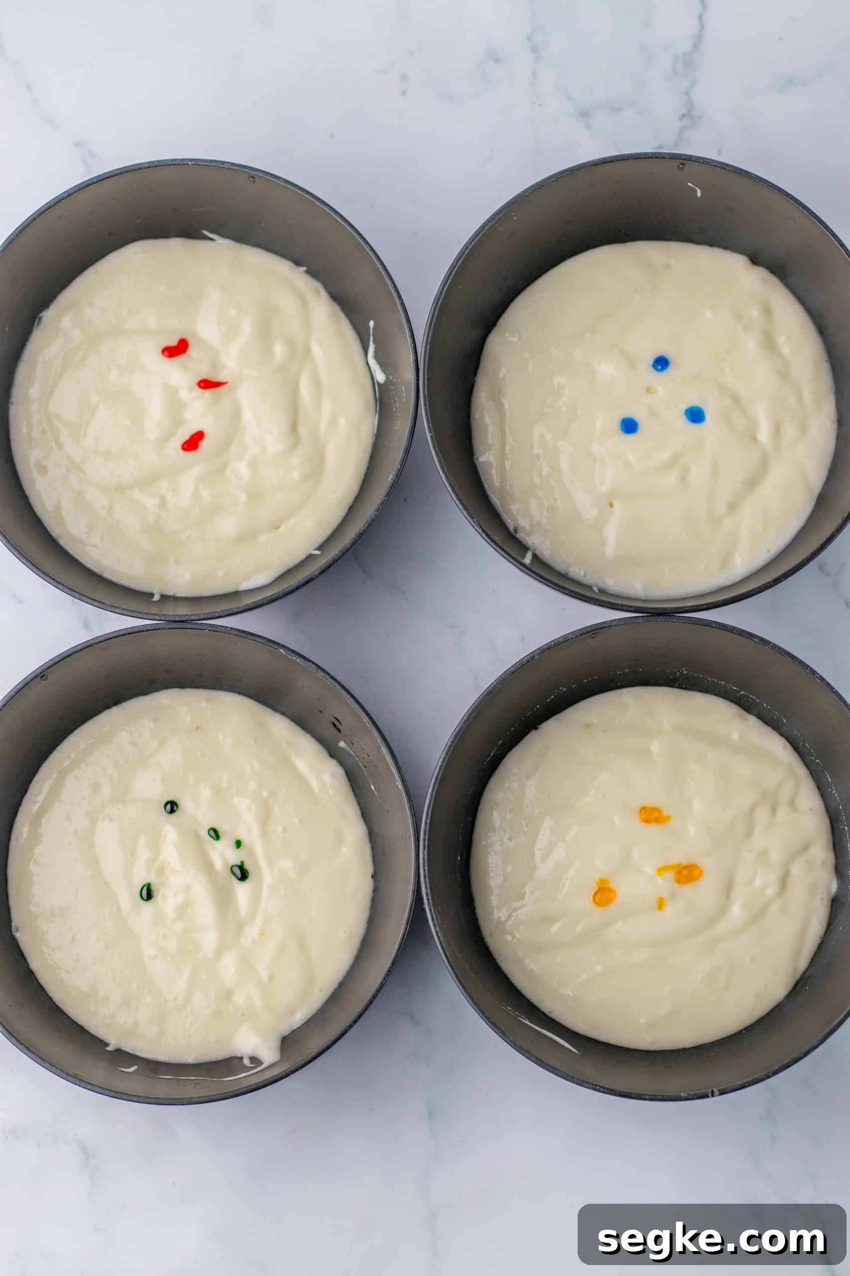 four cake pans filled with cake batter