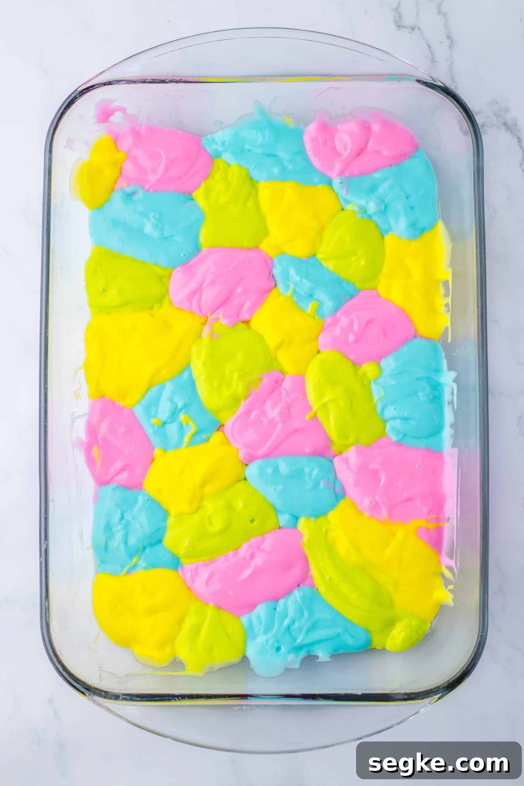 pastel colored dollops of cake batter in a 9x13 inch glass baking dish