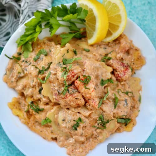 lobster ravioli sauce with lobster meat, lemon wedges, and herbs in a white bowl.