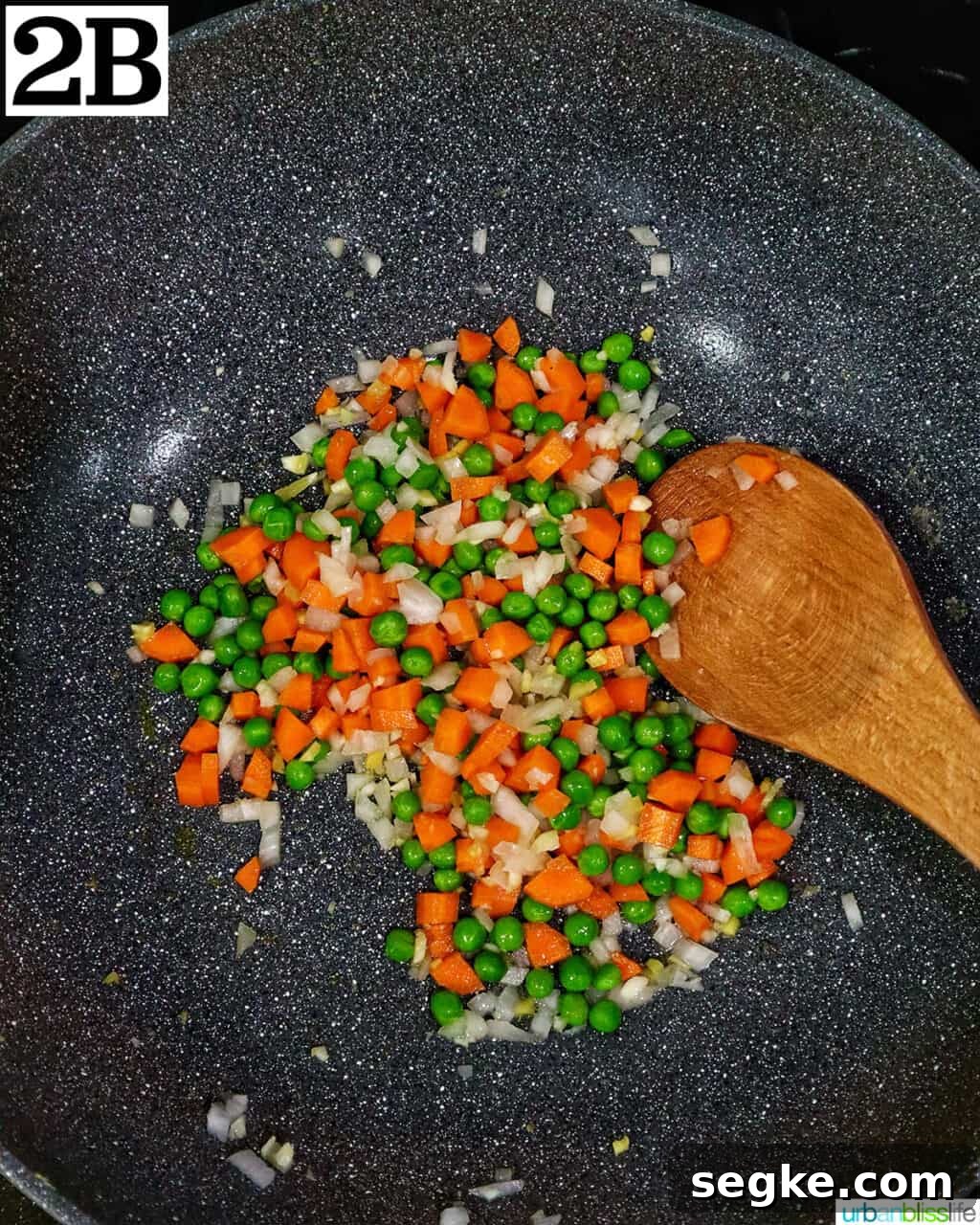 Garlic Butter Lobster Fried Rice 7 wok with vegetables and a wooden spoon.