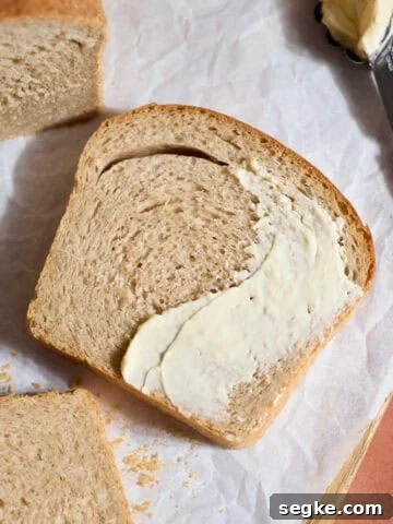 Sourdough Discard Whole Wheat Sandwich Bread slice spread with butter.