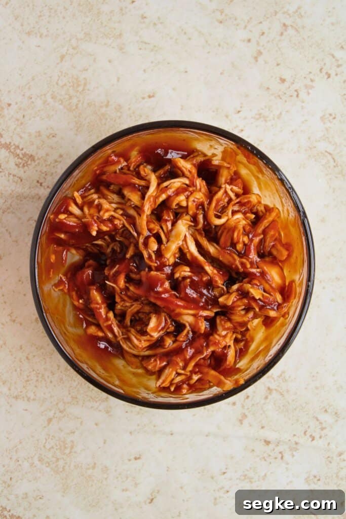 Smoky BBQ Chicken Quesadillas with Melted Cheese 5 Meat being mixed with barbecue sauce.