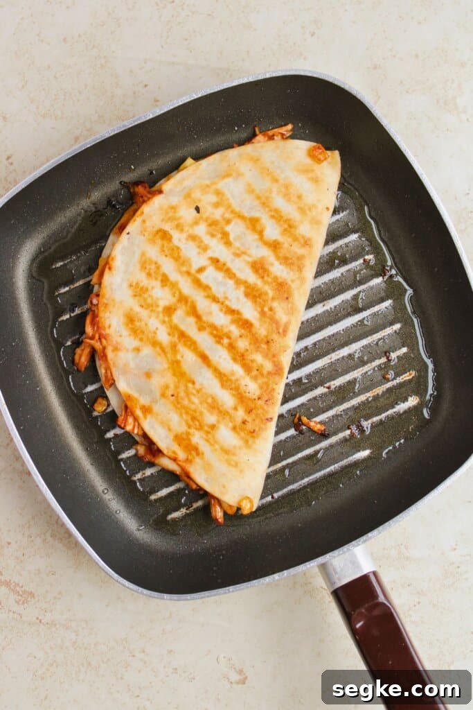 Smoky BBQ Chicken Quesadillas with Melted Cheese 10 Tortilla being browned in a skillet.