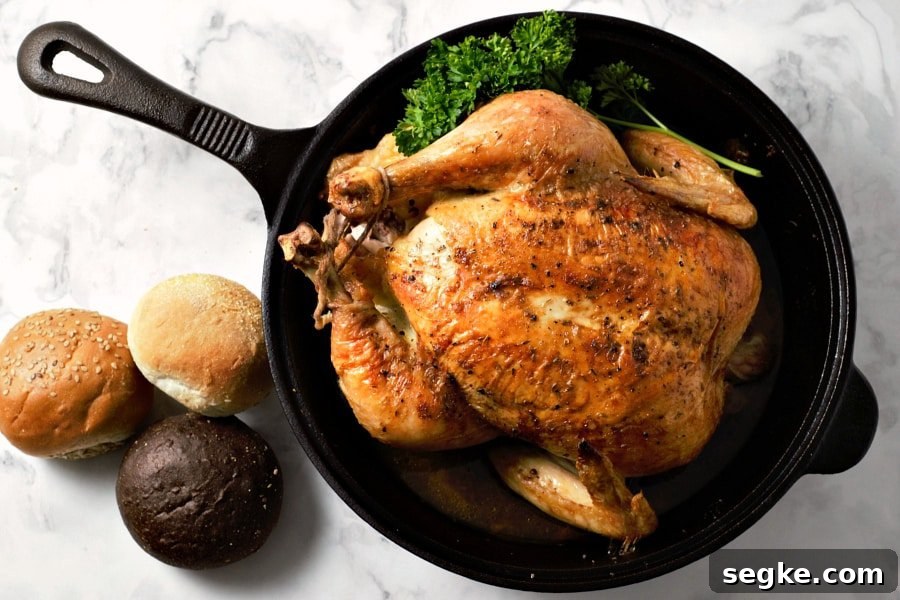 Easy Juicy Whole Roasted Chicken baked in a cast iron skillet.