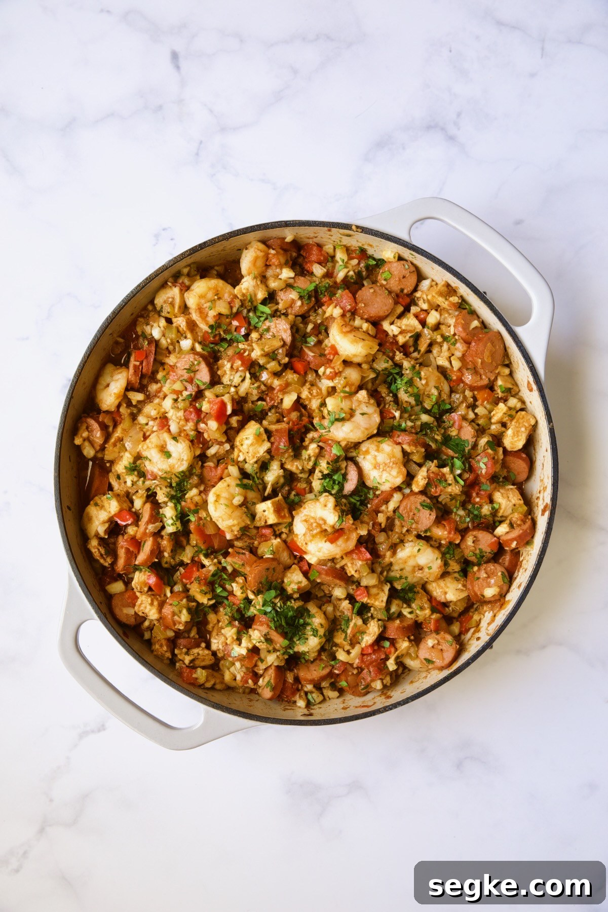 Finished Low-Carb Jambalaya with Chicken Shrimp and Sausage in white enamel cast iron skillet.