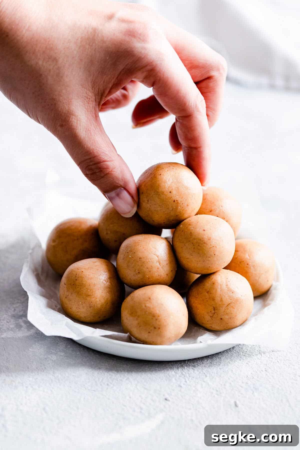 close up of a hand reaching out to peanut butter energy bites