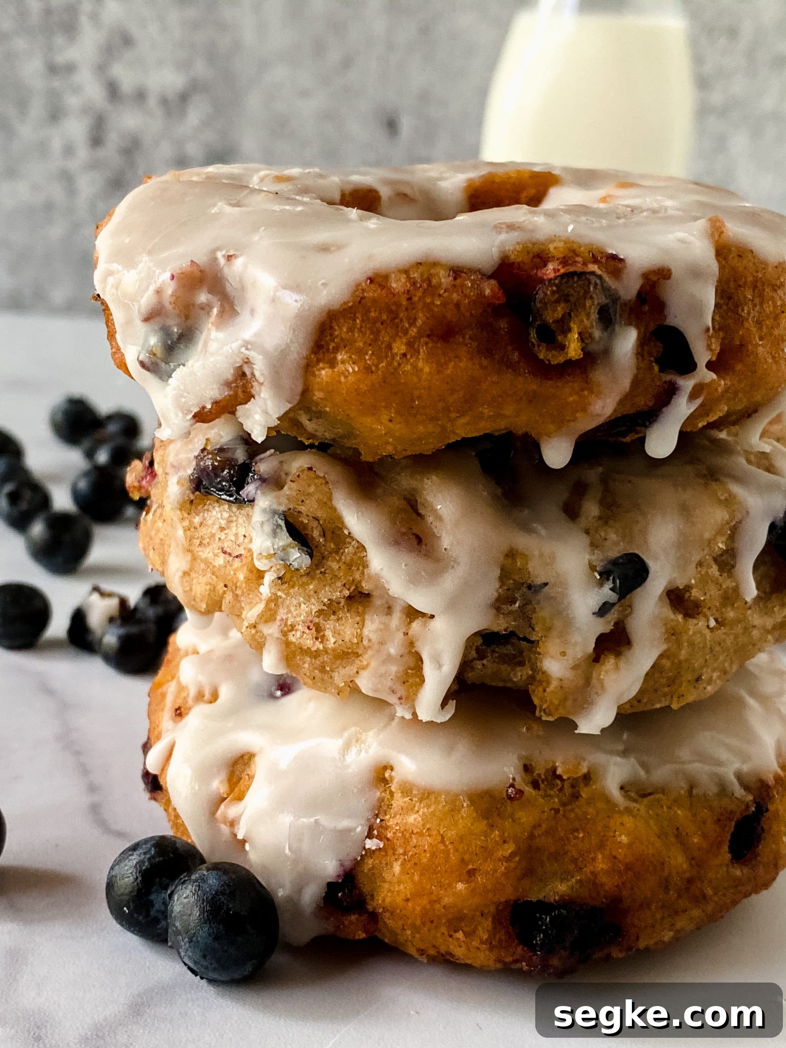 How to Make Homemade Fried Glazed Blueberry Donuts 2 stack of glazed blueberry donuts with close-up.