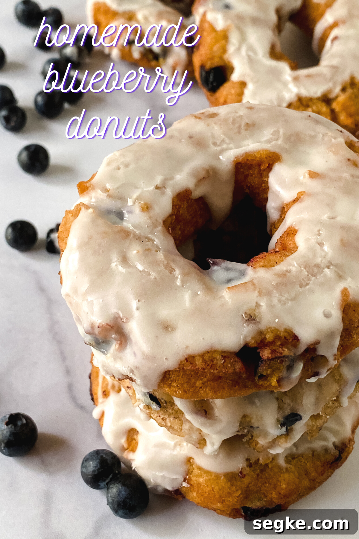 How to Make Homemade Fried Glazed Blueberry Donuts 13 top angled view of a stack of blueberry donuts topped with glaze.