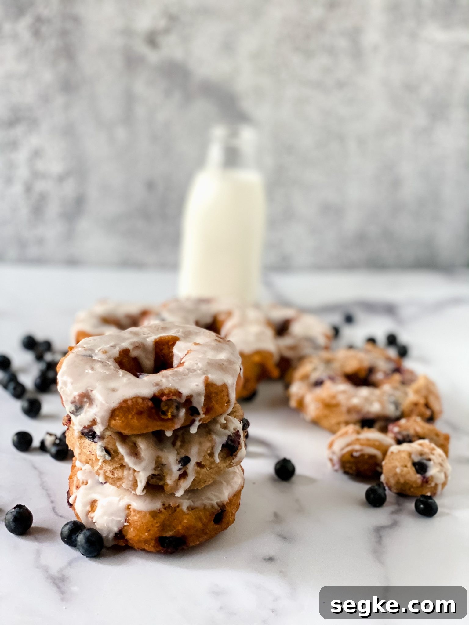 How to Make Homemade Fried Glazed Blueberry Donuts 4 blueberry donuts in front of a bottle of milk.