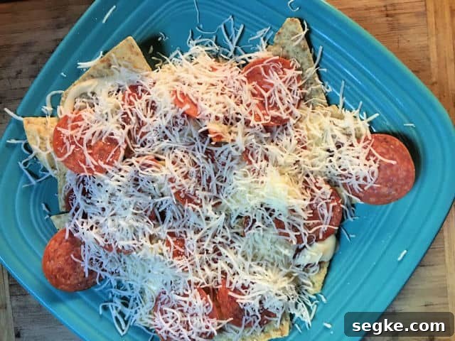 shredded cheese sprinkled over the top of the nachos on blue plate