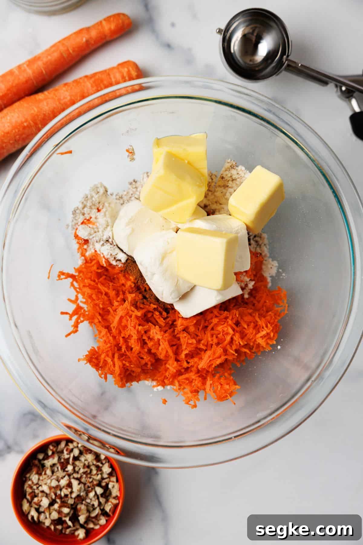 No Bake Keto Carrot Cake Protein Bites 4 Glass bowl with grated carrots, cream cheese, butter, and protein powder before mixing