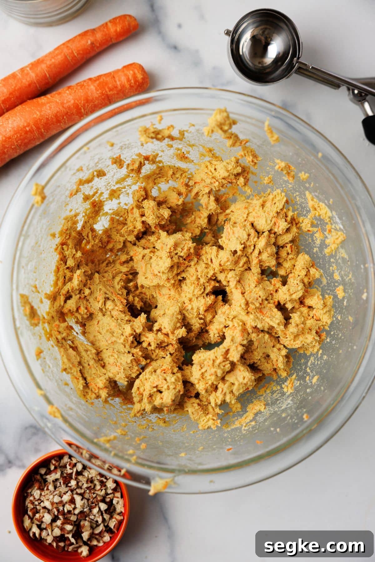 No Bake Keto Carrot Cake Protein Bites 5 Thick golden carrot cake mixture in a glass bowl after mixing, with bits of shredded carrot throughout