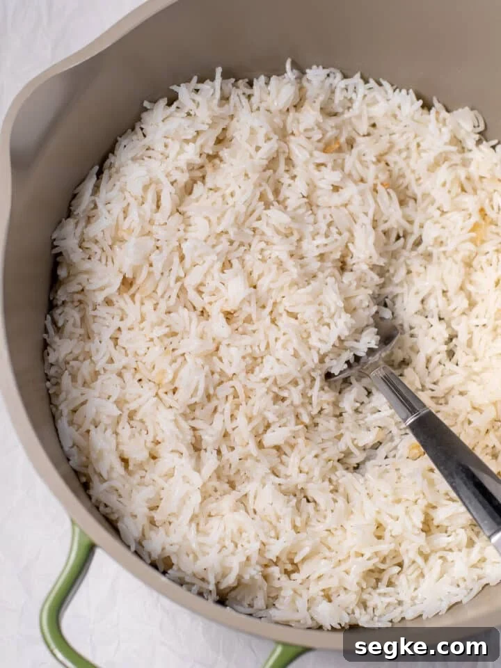 How to Make Fluffy Coconut Basmati Rice 3 cooked rice in a pot with a large fork
