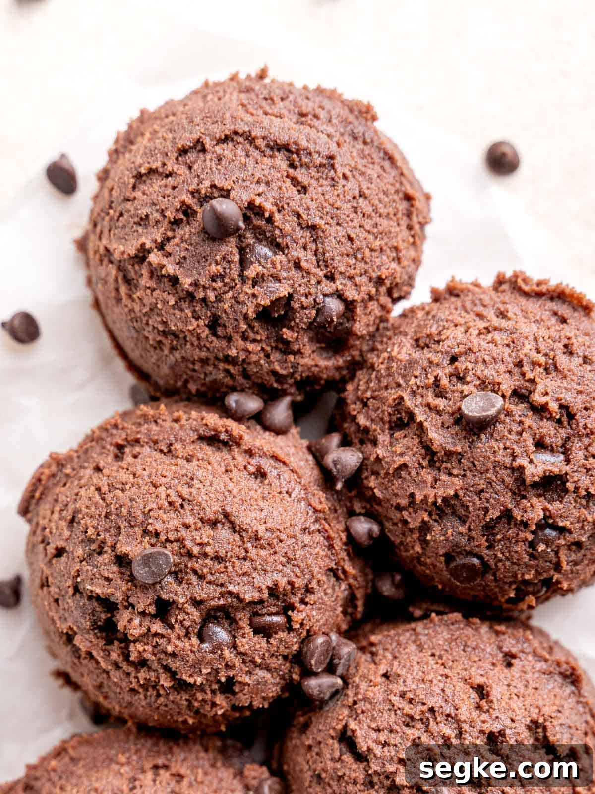 Scoops of chocolate cookie dough on parchment paper.