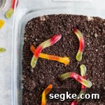 Dirt cake with gummy worms on top in a baking pan.