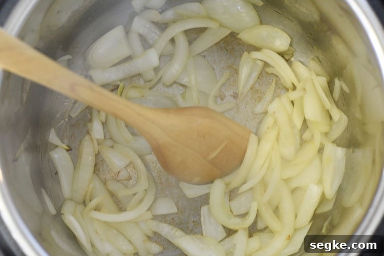 saute cut onions in the instant pot pressure cooker using wooden spoon