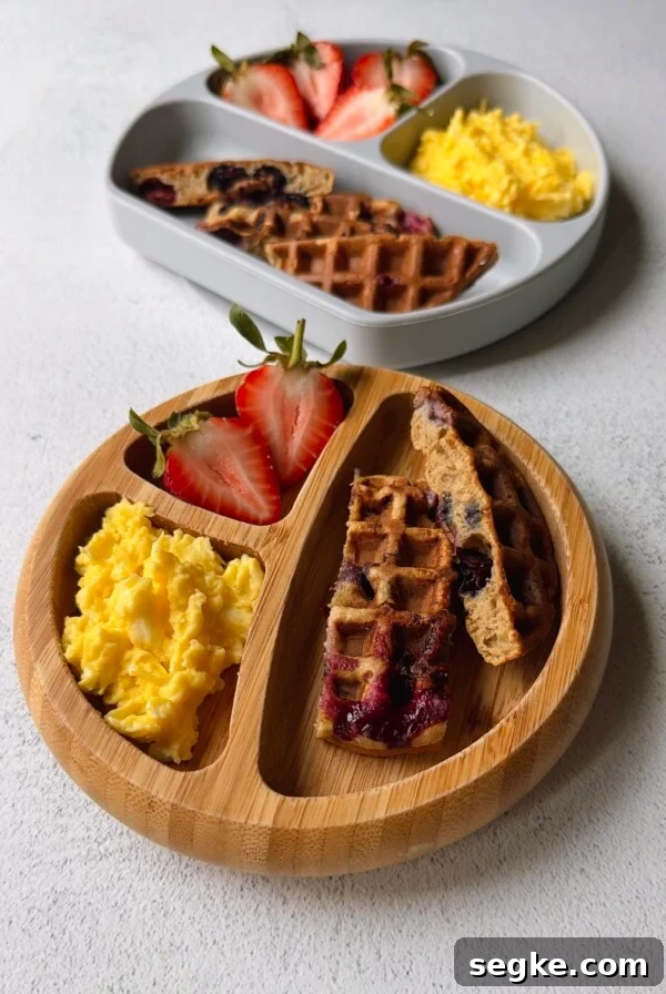 Blueberry banana waffles served with strawberries and scrambled eggs.