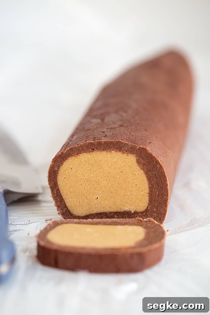 Log of cookie dough on wax paper with a slice cut