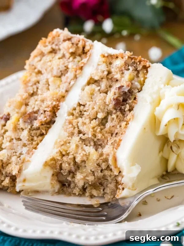 Slice of cream cheese frosted hummingbird cake on a white plate