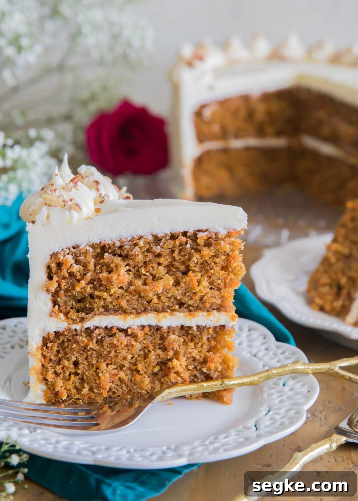 Moist Spiced Carrot Cake with Cream Cheese Frosting 6 a slice of frosted carrot cake on a white plate with the rest of the cake in the background