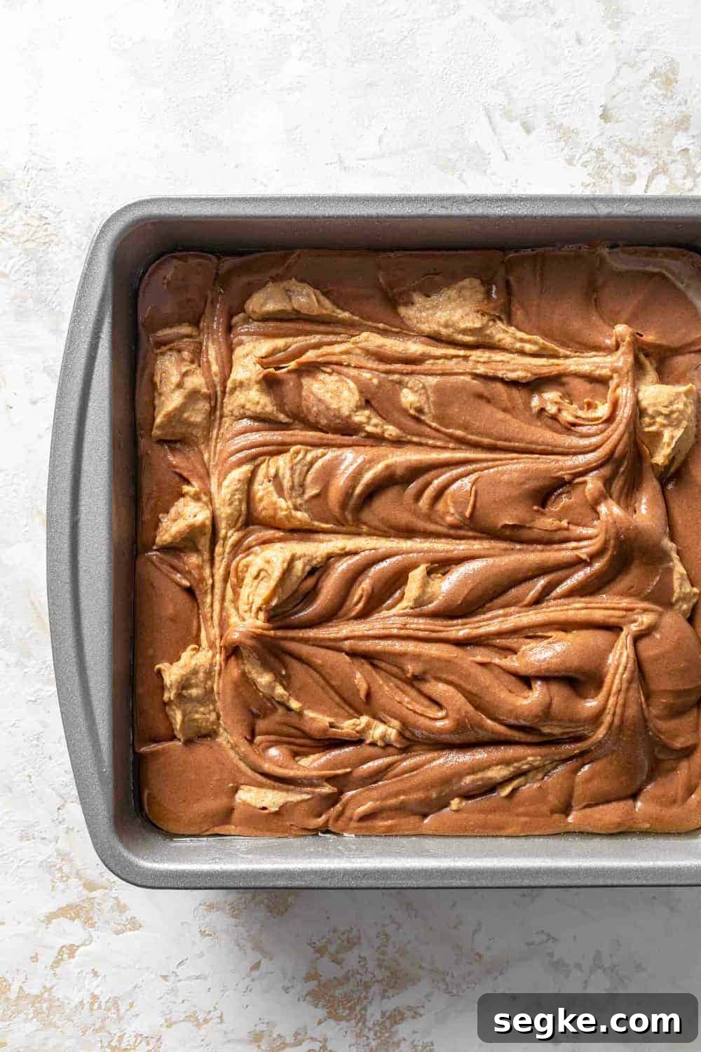 Fudgy Pumpkin Brownies with Cinnamon Chocolate Swirl 5 Brownie batter swirled with a pumpkin cream cheese mixture in a pan, ready to bake