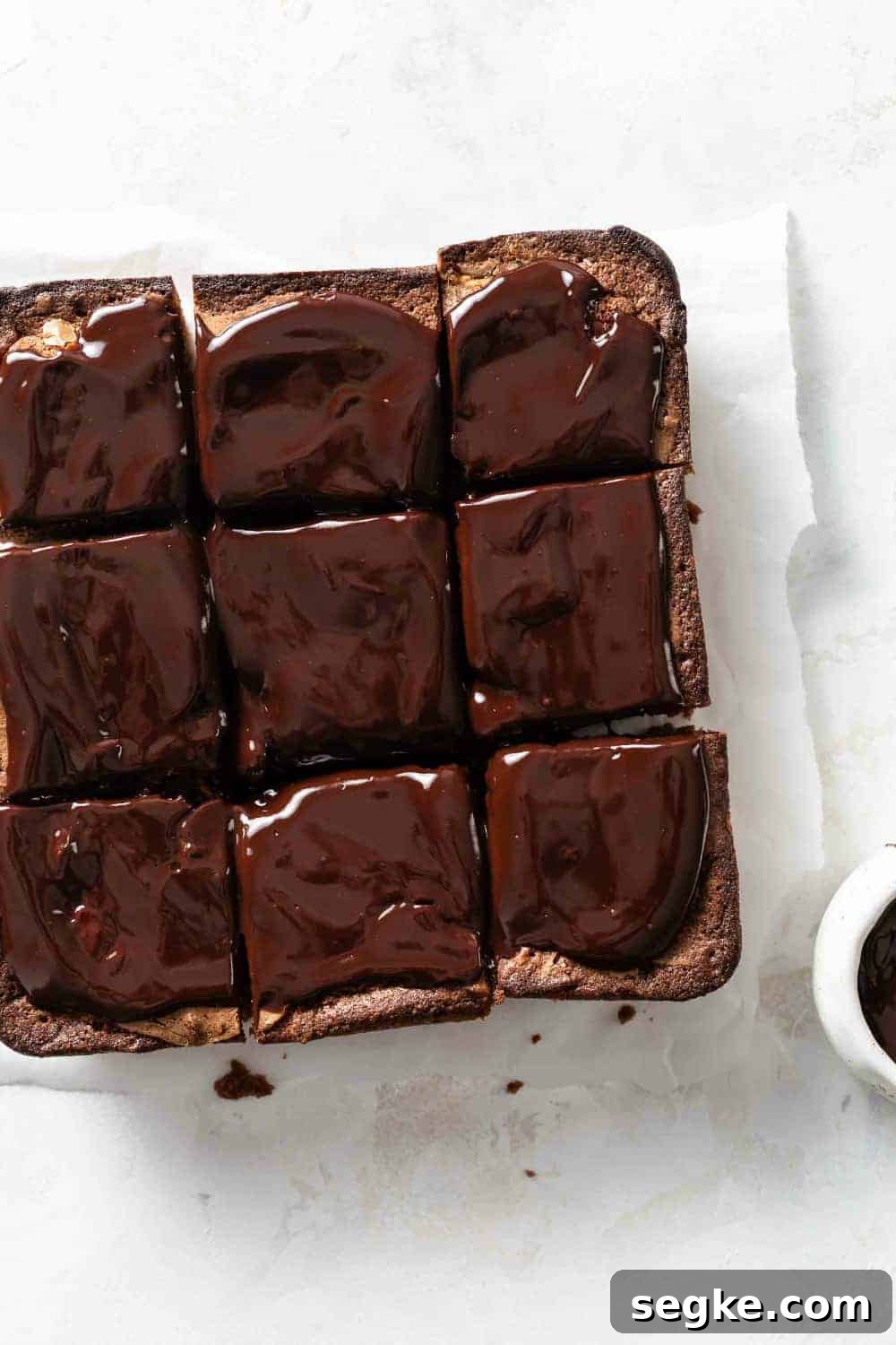 Fudgy Pumpkin Brownies with Cinnamon Chocolate Swirl 7 Sliced pumpkin brownies topped with chocolate ganache on a piece of parchment