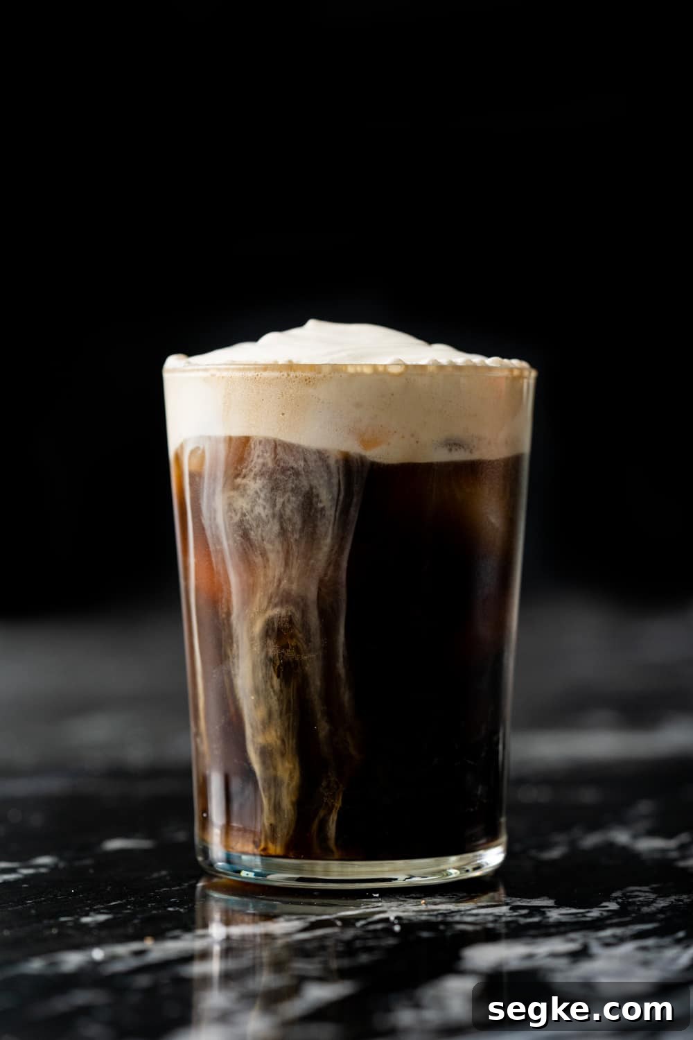 A homemade salted caramel cream cold brew on a black marble table