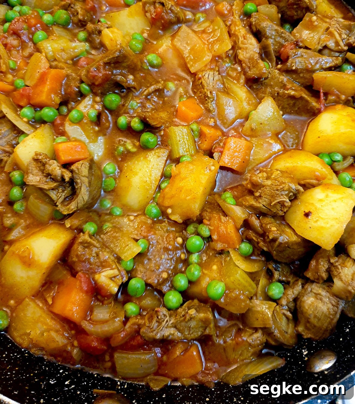 Close up of leftover lamb curry with potatoes, peas and other vegetables.