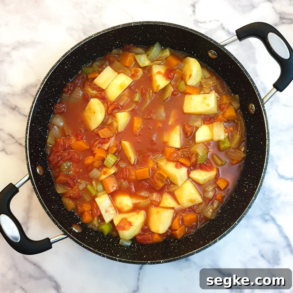 Raw potatoes, stock and tinned tomatoes added to the lamb curry.