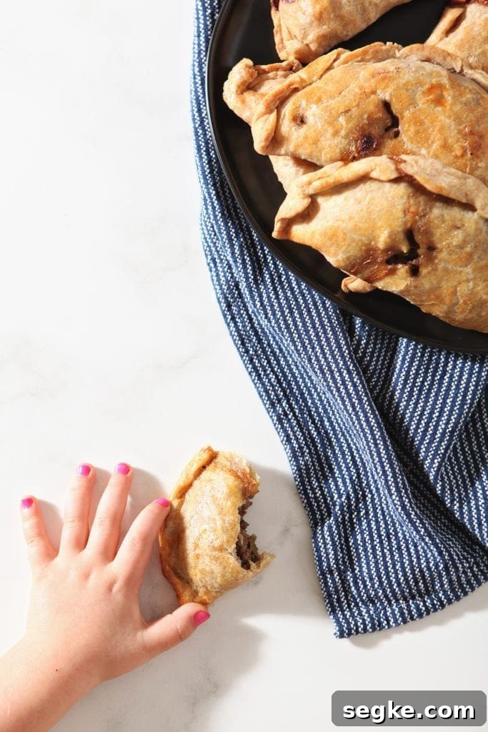 A girl grabs a halved meat pie, from above
