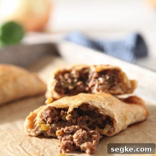 A halved meat pie is shown on a baking sheet, with ingredients in the background
