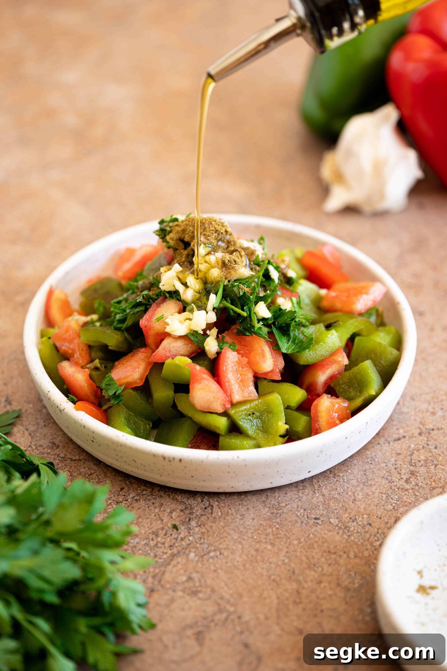olive oil drizzling over a bowl of roasted pepper salad