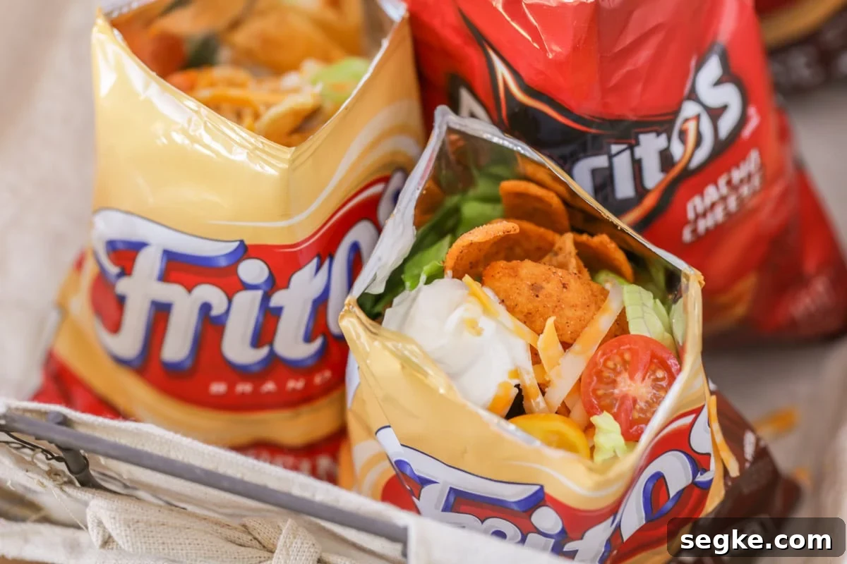 Walking tacos are an easy grab-and-go meal that is full of flavor! They are no mess, easy to make, and perfect for large gatherings!! Walking tacos served in small chip bags.