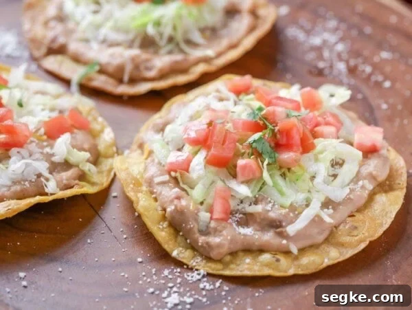 Walking Tacos: Portable Taco Cups for Parties and Tailgates 8 Three tostadas topped with refried beans, lettuce, tomatoes, and cilantro.