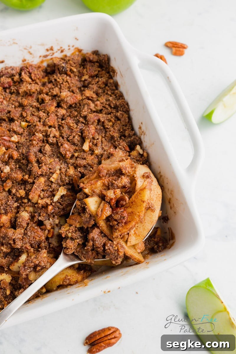 a spoon taking a serving of paleo apple crisp from the pan