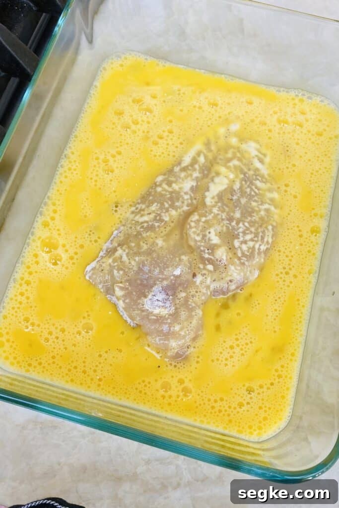 Dipping floured chicken in egg wash.