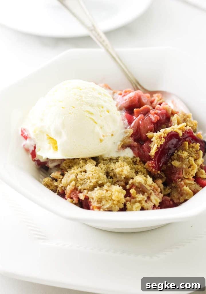 Strawberry Rhubarb Crisp Recipe 2 A serving dish filled with strawberry rhubarb crisp and vanilla ice cream.