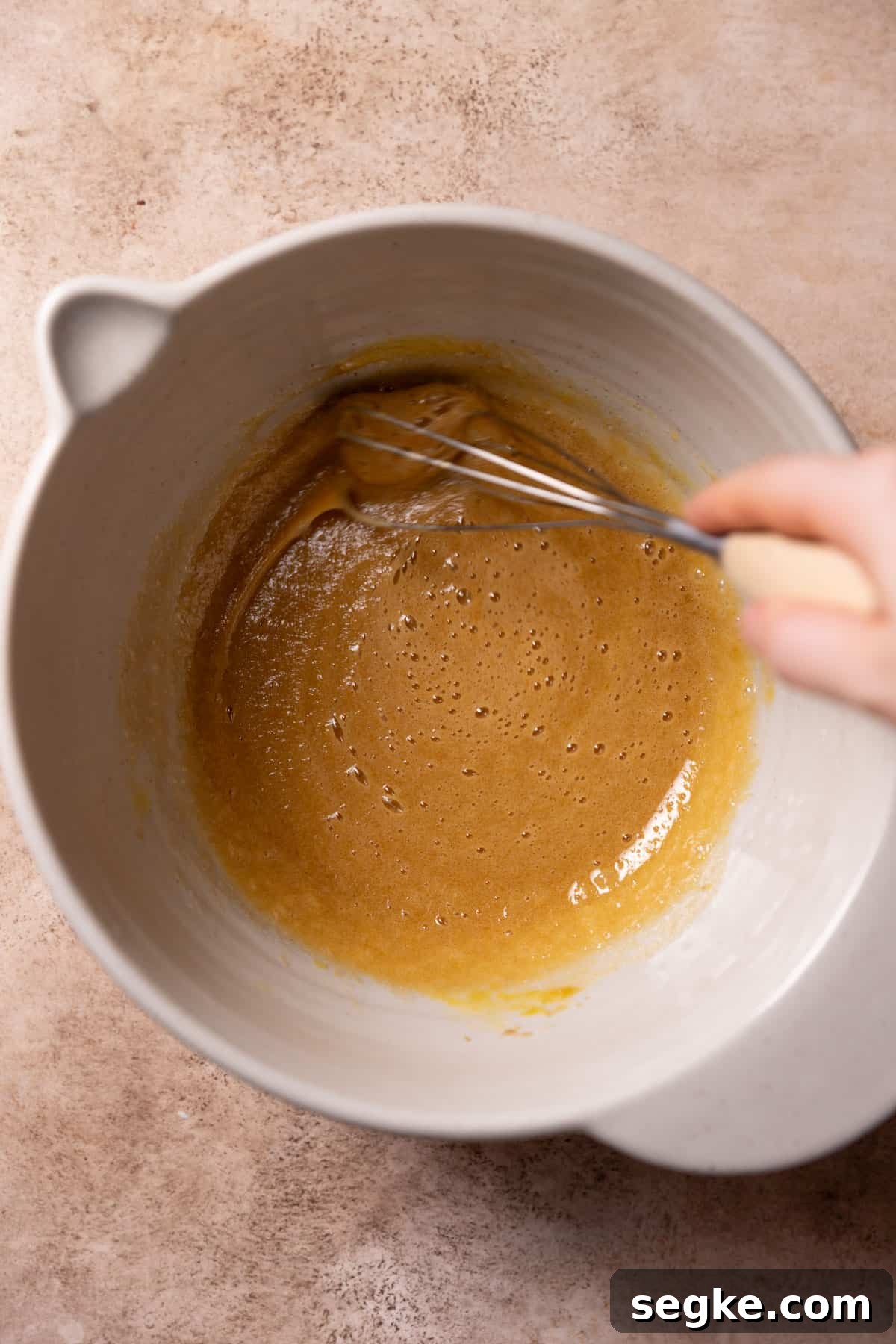 whisking the eggs and sugar together in a mixing bowl.