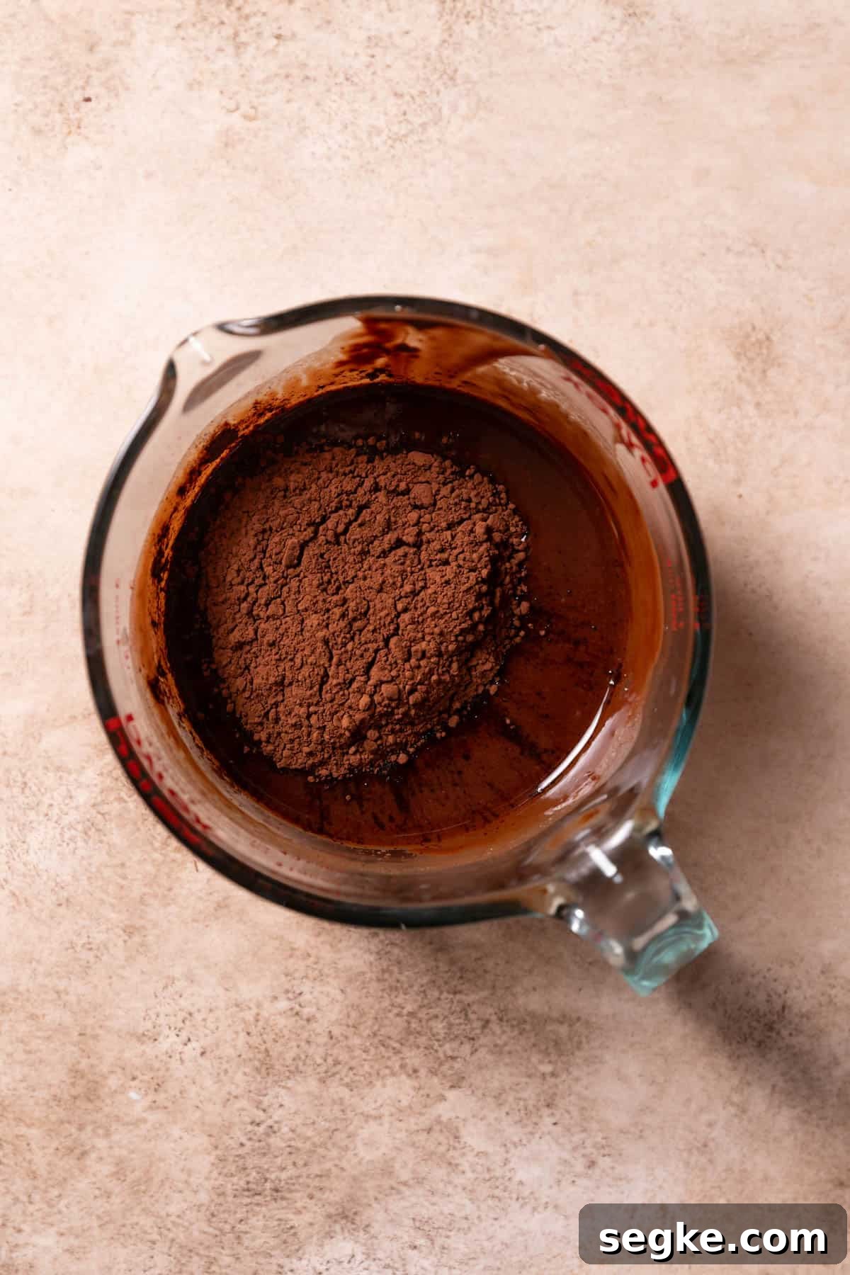 melted butter and chocolate in a bowl with cocoa powder on top.