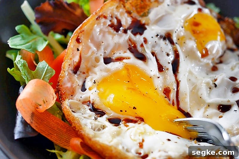 A fork is popping the runny yolk in a Sunnyside Salad