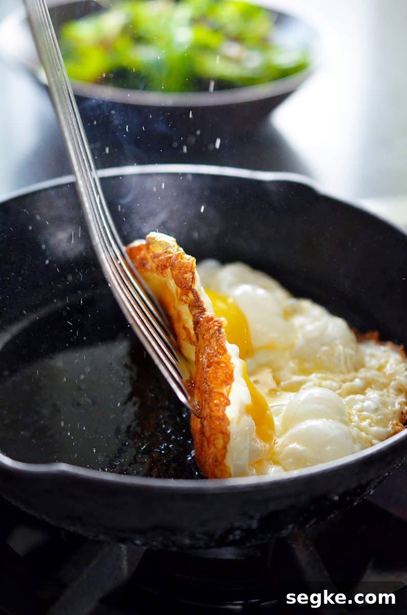 A thin spatula lifts up the crispy egg to expose the browned whites on the bottom.