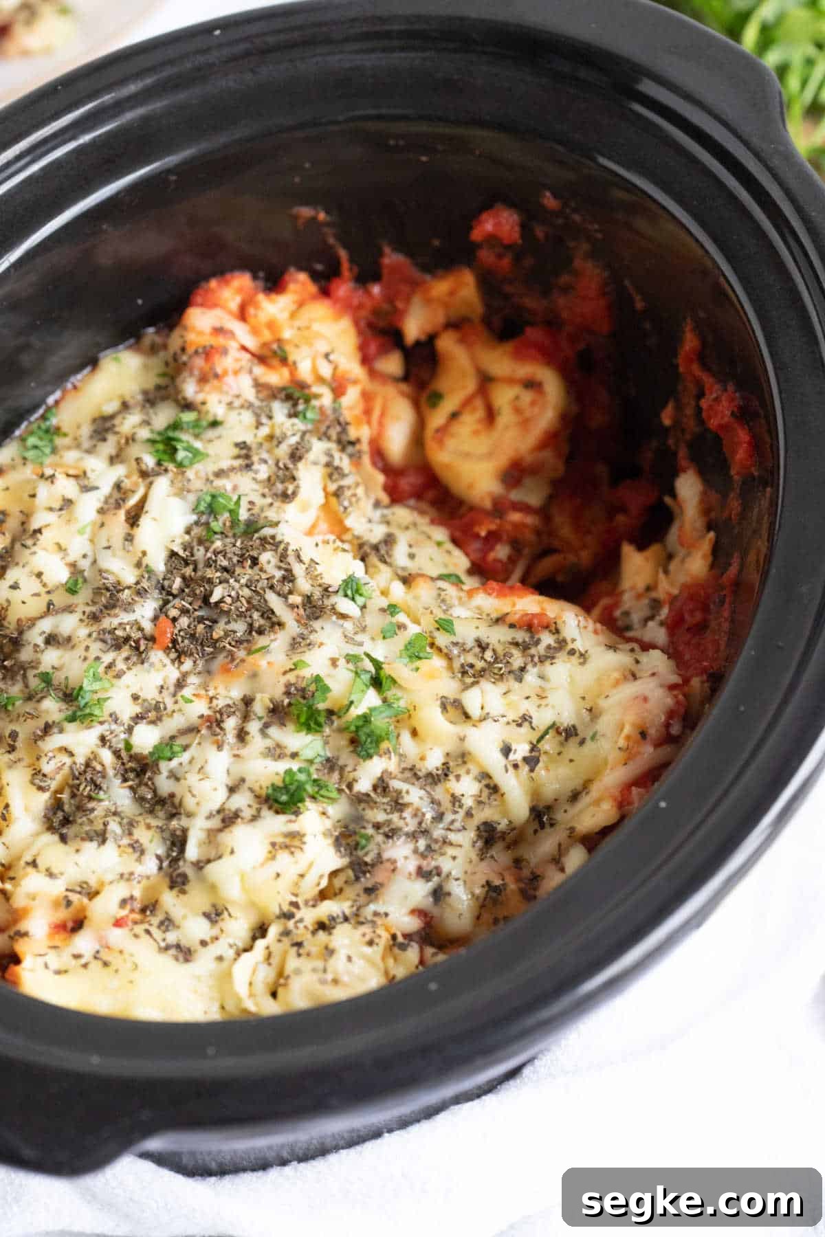 Slow cooker cheesy tortellini in a black crockpot.