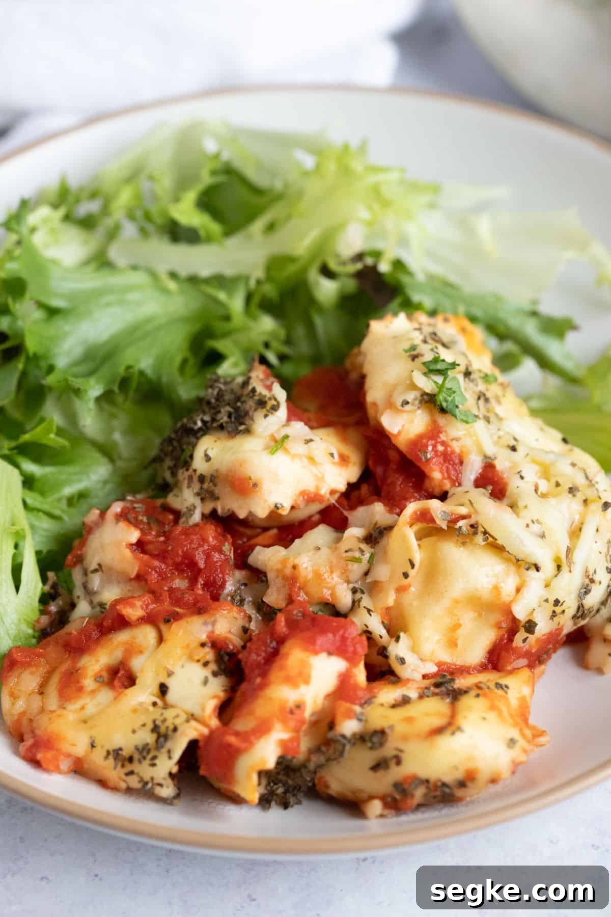Cheesy slow cooker tortellini on a dinner plate with a green salad.