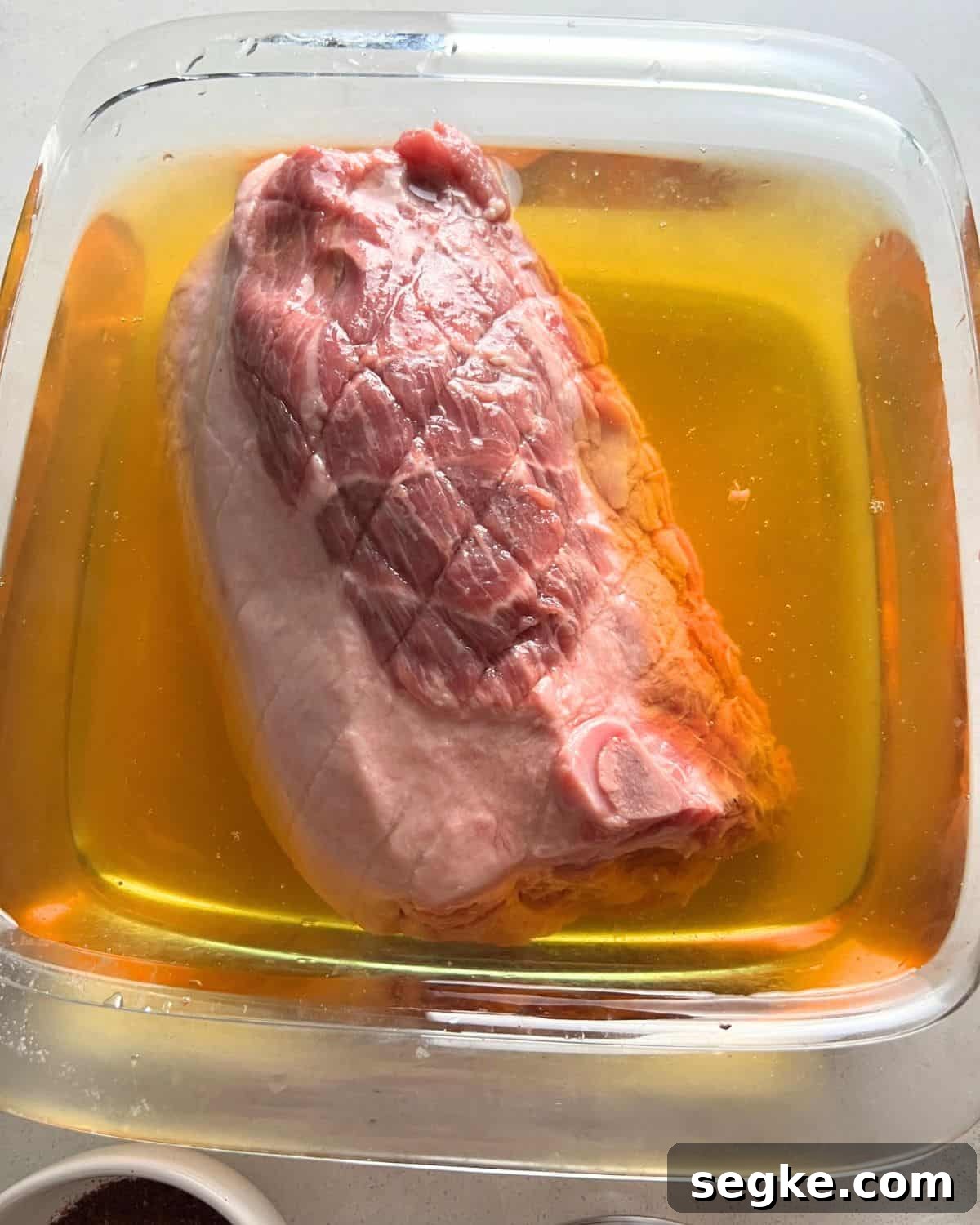Pork shoulder roast brining in a bowl.