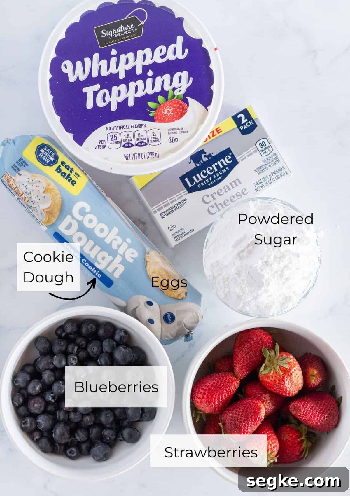 Ingredients for flag fruit pizza: sugar cookie dough, cream cheese, powdered sugar, whipped topping, strawberries, blueberries.